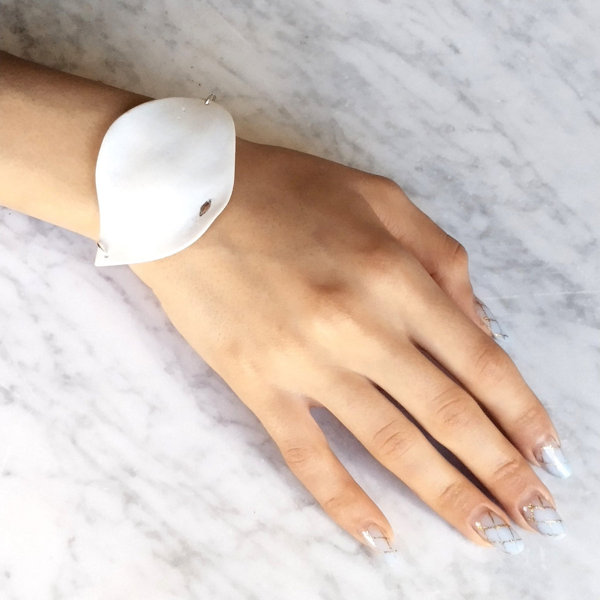 Bracciale Soffio Maviart indossato al polso, porcellana bianca con inclusione in platino e catena in argento