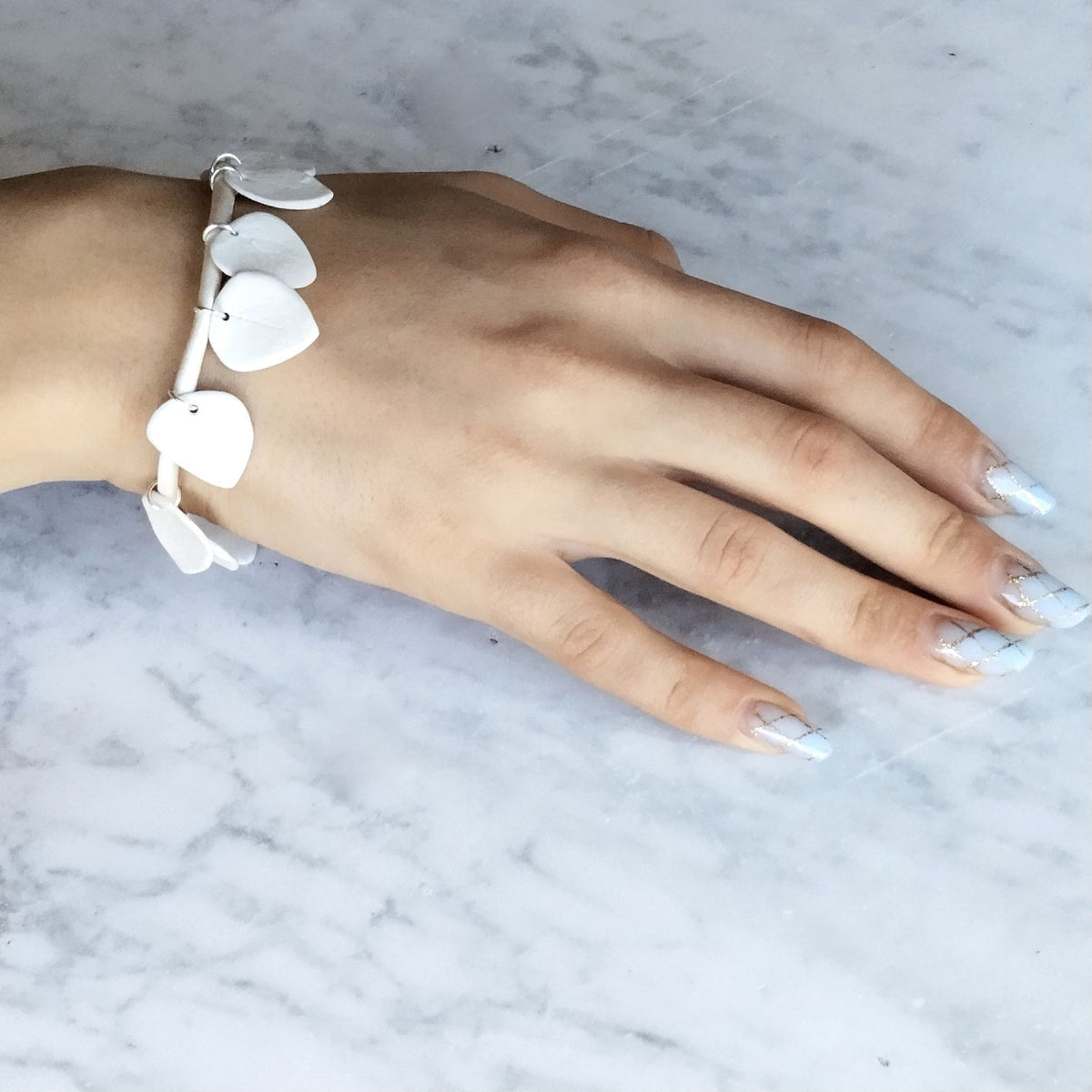 Bracciale Foglie Maviart indossato al polso, porcellana bianca e inserti in argento