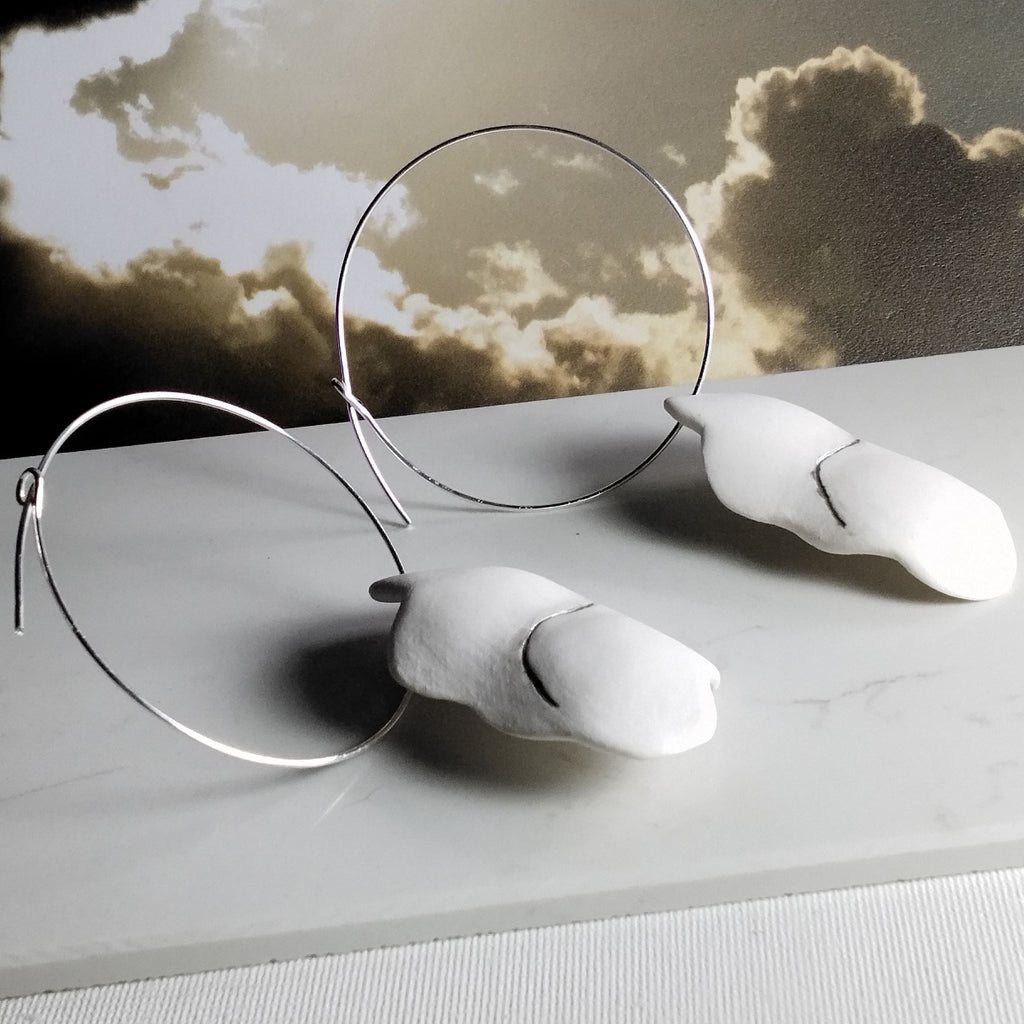 Foto 2: Orecchini Cumulo con cerchi in argento e pendenti in porcellana bianca con platino, fotografati con uno sfondo di nuvole.