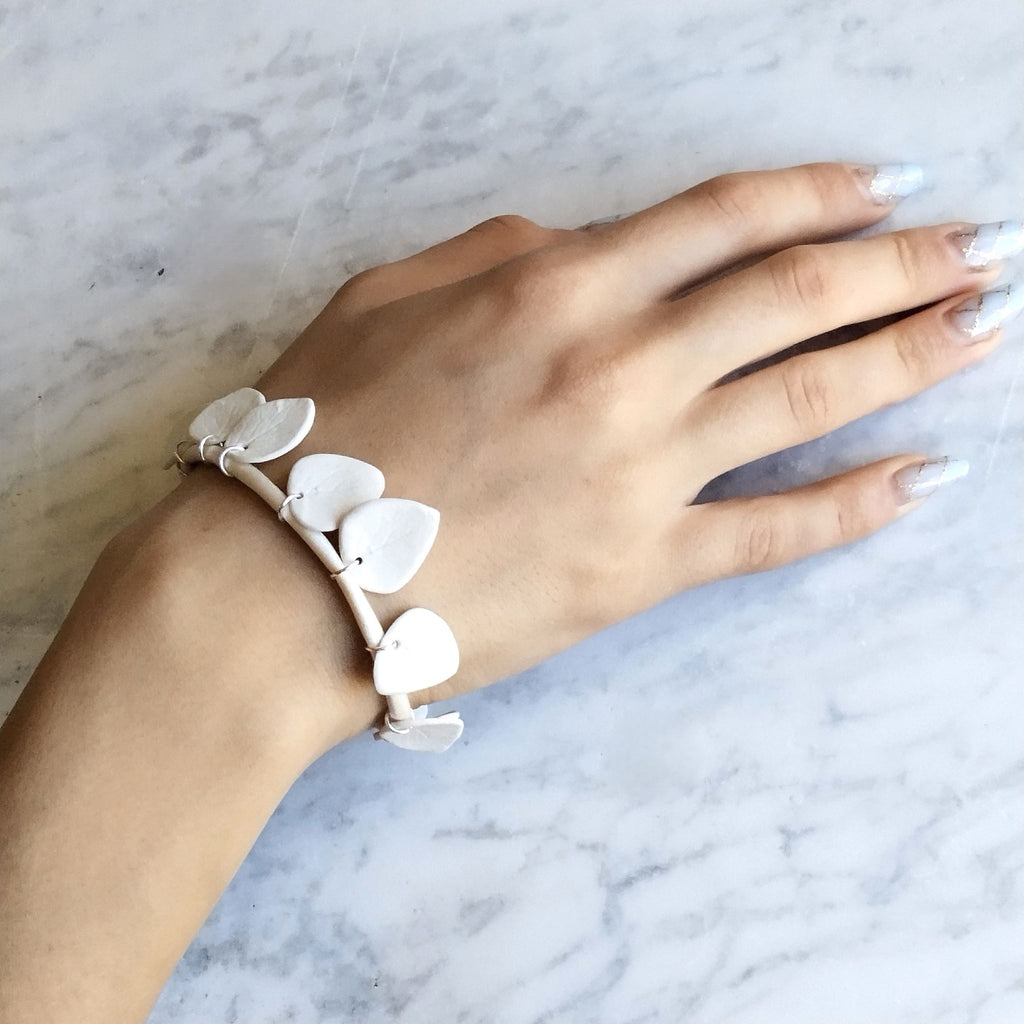 Bracciale Foglie Maviart indossato, ripreso in posa dall'alto, porcellana bianca e inserti in argento