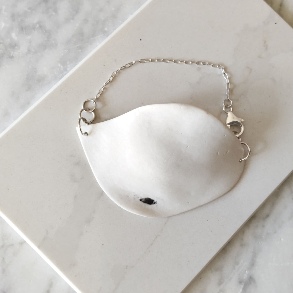 Bracciale Soffio Maviart in posa dall'alto: porcellana bianca e catena in argento sterling