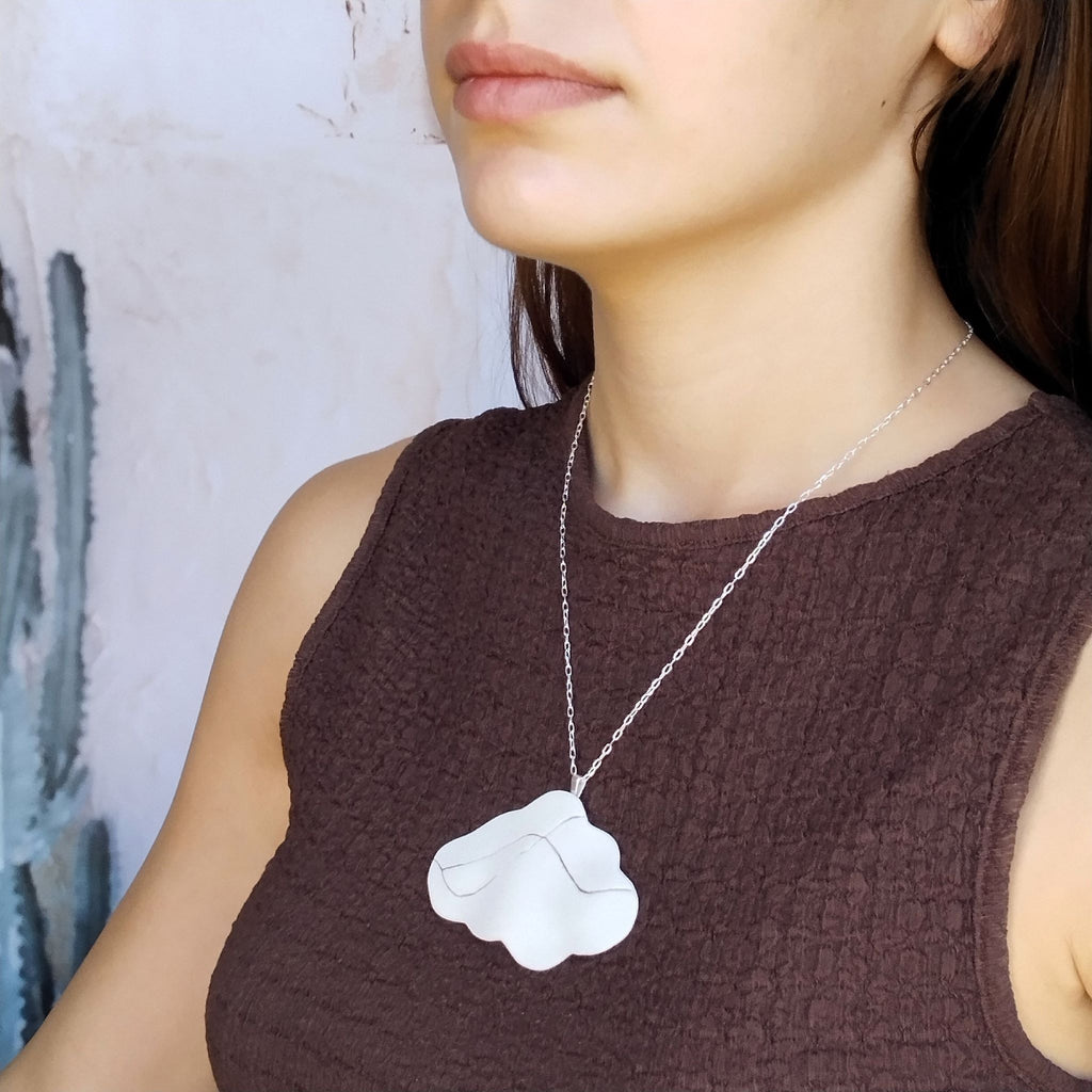 Collana Cumulo Maviart indossata su un top scuro, con pendente a forma di nuvola in porcellana bianca e catena in argento.