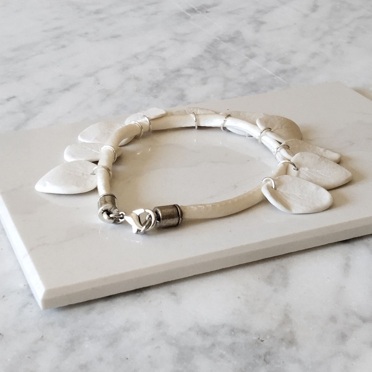 Dettaglio chiusura in argento. Bracciale foglie in porcellana bianca opaca con inserti in argento, Collezione Aria