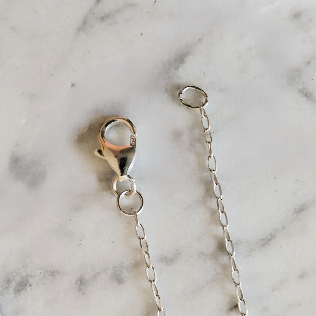 Dettaglio della chiusura a moschettone e delle maglie della catena in argento della collana Soffio.