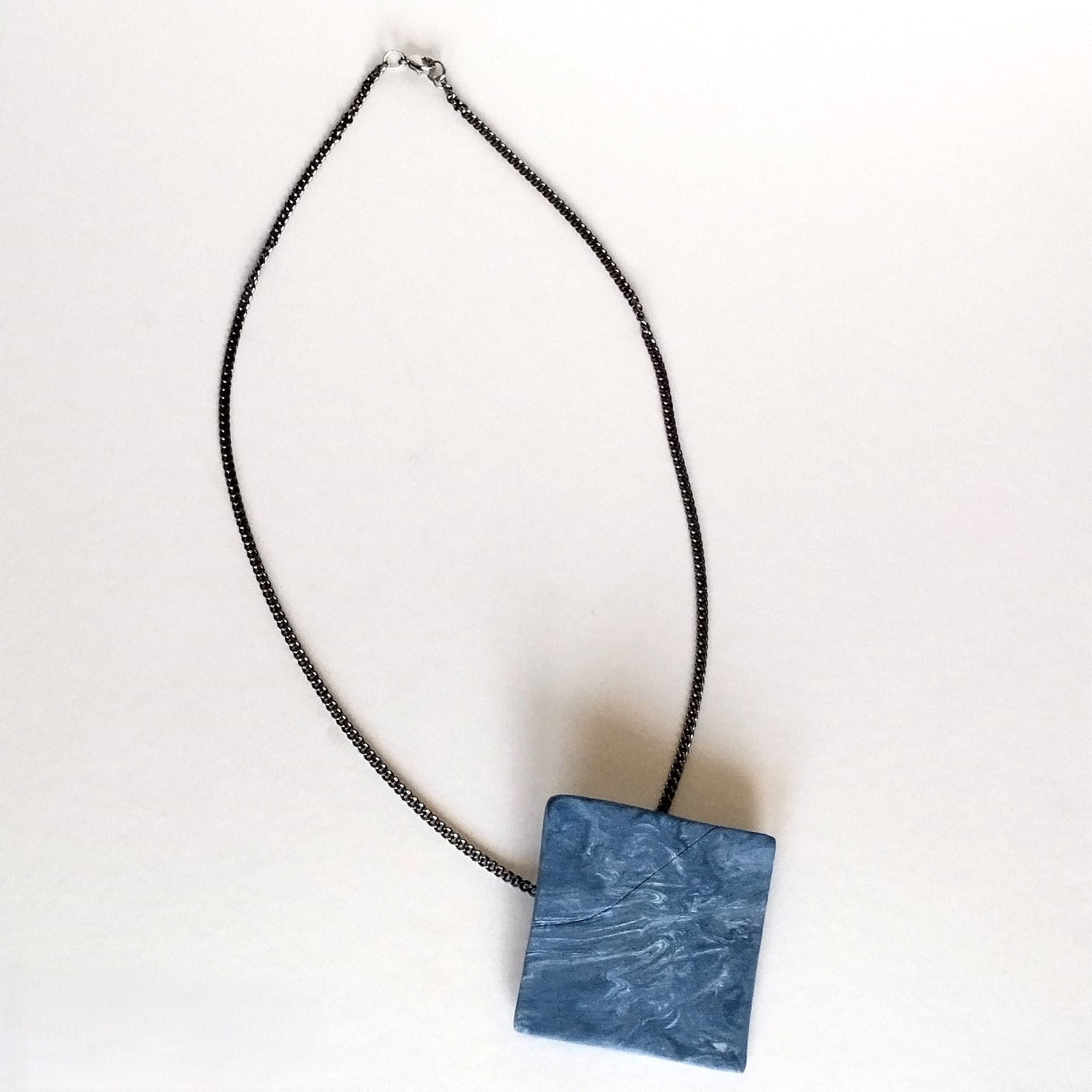 Collana con pendente romboidale in porcellana nerikomi colori del mare, posa dall'alto su cartoncino bianco – Maviart