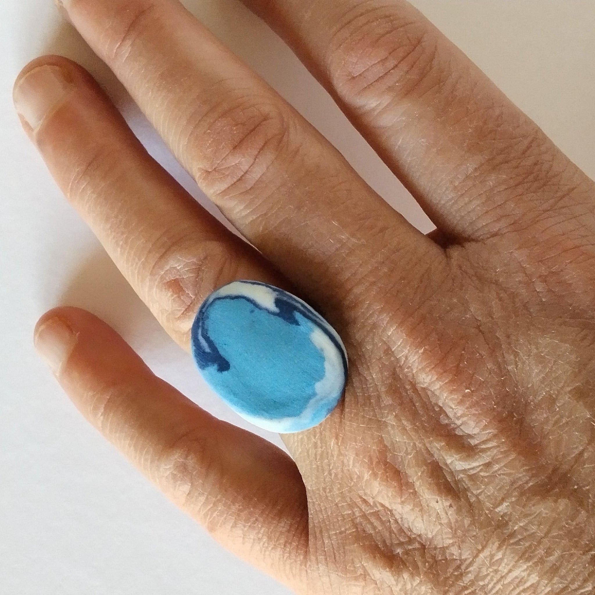 Anello ovale, porcellana nerikomi, colori del mare, indossato.