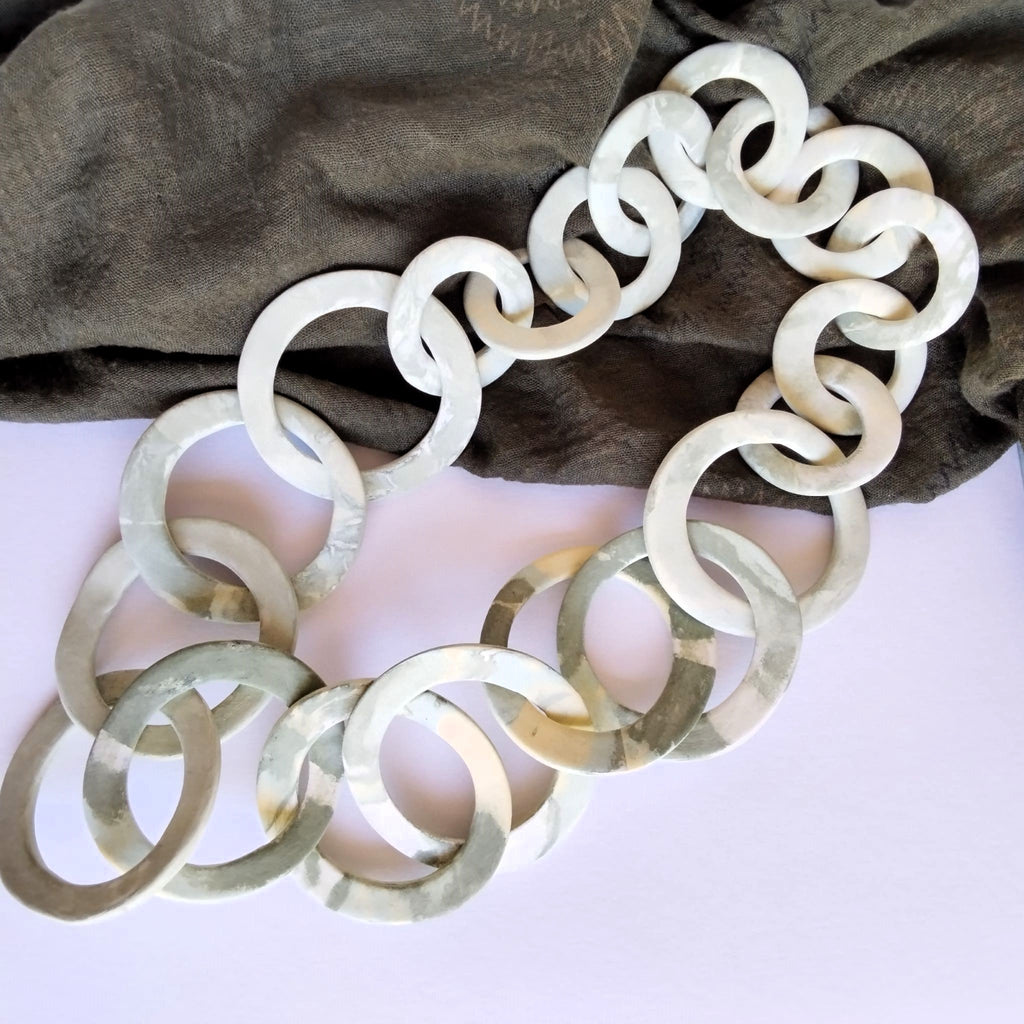 Collana a maglie circolari in porcellana nerikomi colori della terra — posa dall'alto su sfondo bianco  Maviart