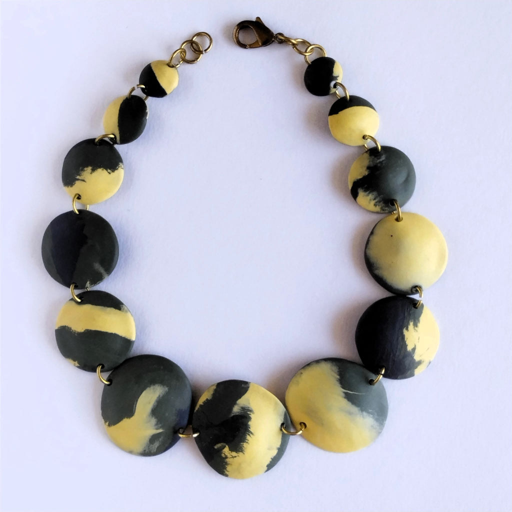 Collana nerikomi porcellana artigianale elementi convessi nero, verde e giallo ocra, silhouette completa su sfondo bianco – Maviart